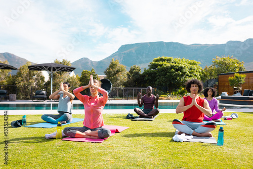 Diverse friends practicing yoga and meditating in garden
