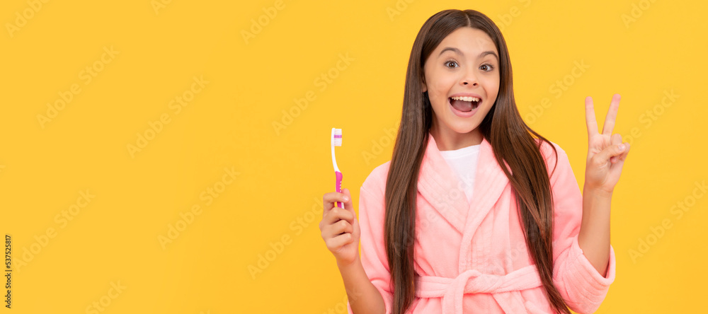 happy amazed teen girl in home terry bathrobe hold toothbrush show peace gesture, childhood. Banner of child girl with teeth brush, studio portrait, header with copy space. happy amazed teen girl in home terry bathrobe hold toothbrush show peace gesture, childhood. Banner of child girl with teeth brush, studio portrait, header with copy space.