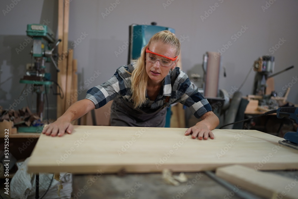 Contemporary Carpenter Working, Portrait of modern carpenter making wood furniture while working in joinery lit by sunlight with factory background on small business concept, copy space Contemporary Carpenter Working, Portrait of modern carpenter making wood furniture while working in joinery lit by sunlight with factory background on small business concept, copy space