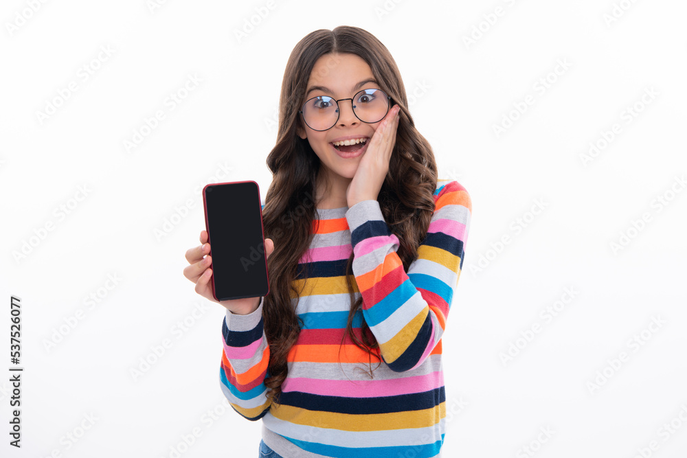 Mobile online shopping. Cute teen child girl paying with phone, texting and chatting on smartphone. Kid showing blank screen mobile phone, mock up copy space.