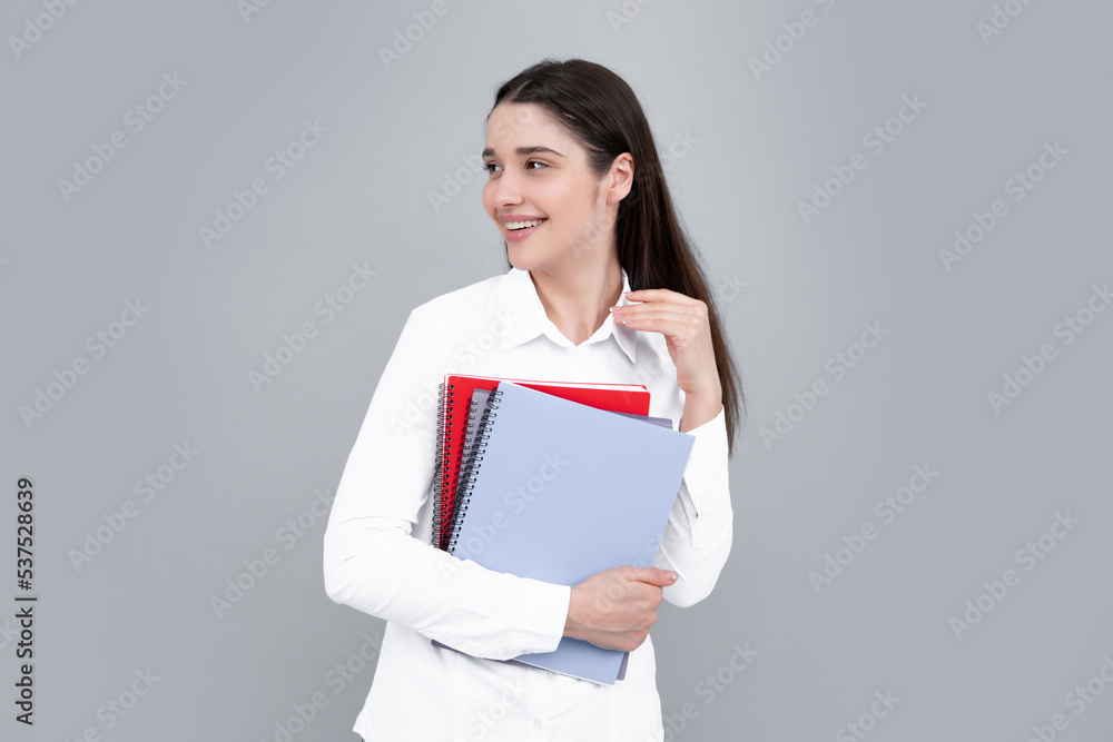 Portrait of student woman. College or high school ducation. Young woman with notebooks smiling at camera on gray studio background. Young female university student. Portrait of student woman. College or high school ducation. Young woman with notebooks smiling at camera on gray studio background. Young female university student.