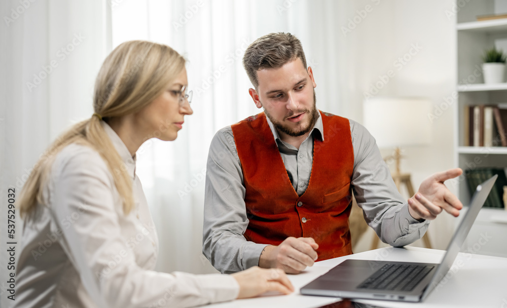 Young handsome designer working with woman client in office, discussing an idea and visualization it on laptop Young handsome designer working with woman client in office, discussing an idea and visualization it on laptop