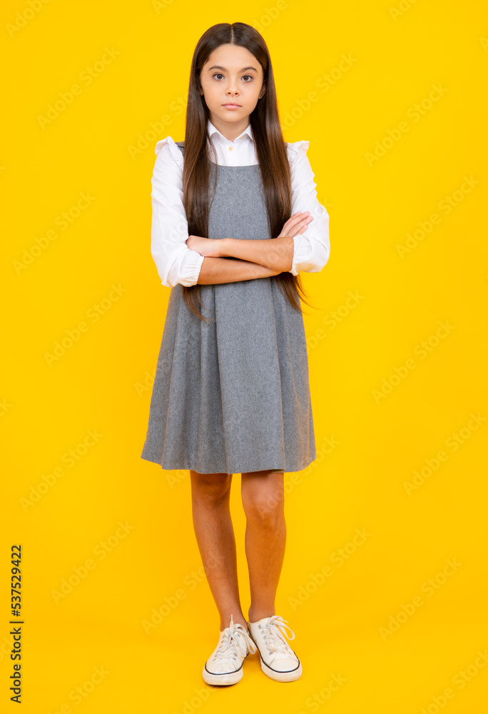 School uniform. Full length of pretty cheerful teenager girl having fun good mood and posing in casual clothes isolated over yellow background. School uniform. Full length of pretty cheerful teenager girl having fun good mood and posing in casual clothes isolated over yellow background.