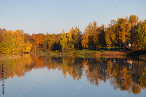 Trees in brilliant autumn color reflecting in a small lake in Latvia