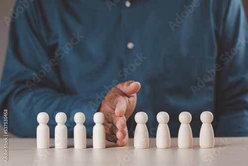 A businessman's hand divides the wooden figure into two sides, a man and a woman. Concept of gender equality teamwork, unity, gender division. Wooden puppet.