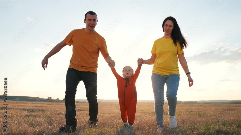 Happy family silhouette on background of sun. Father, mother, child run towards sunset. Child jump with pleasure on green grass of park. Travel, happy parents walk with child in summer in family park Happy family silhouette on background of sun. Father, mother, child run towards sunset. Child jump with pleasure on green grass of park. Travel, happy parents walk with child in summer in family park