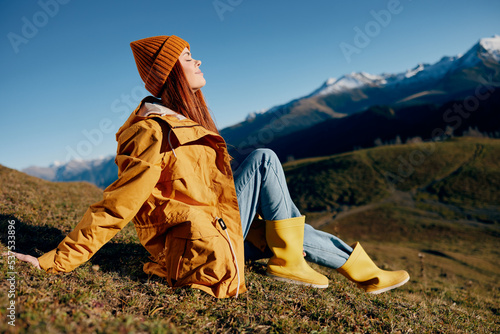 Canvas Print Woman sitting on a hill on the grass rest smile with teeth looking at the mounta