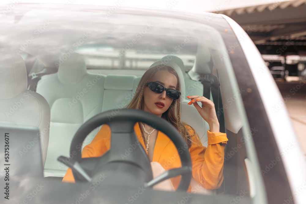 Naklejka premium Schöne Junge Frau bei Elektro Auto Fahren durch die Grüne umweltfreie Stadt
