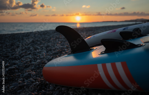 sup board fin close-up at sunset by the sea