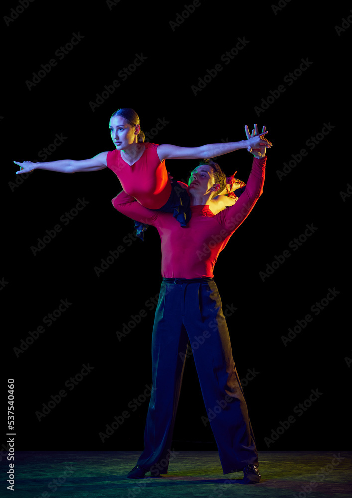 Obraz premium Support. Sensual young dancers dancing ballroom dance isolated on dark background. Concept of art, dance, beauty, music, style.