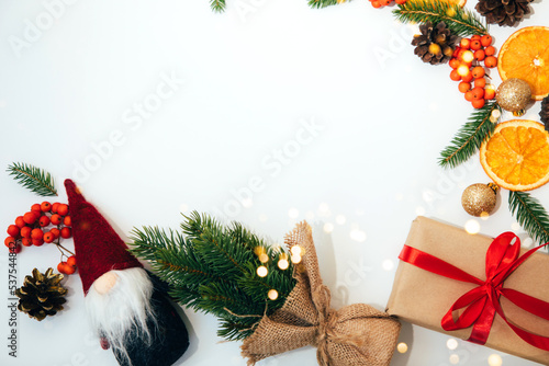 New Year's, Christmas background, decor on a white table with branches of a green fir, pine cones, gnome and orange. Flay lay