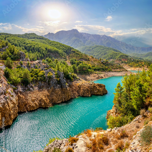 Fotografie Beautiful landscape of mountainous nature with bright summer sun, blue sky, high mountains, green hills, yellow rocks and turquoise water lake