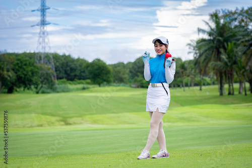 Portrait happiness beautiful professional golfer showing red heart ball holding by glove golf with green grass at golf course background.