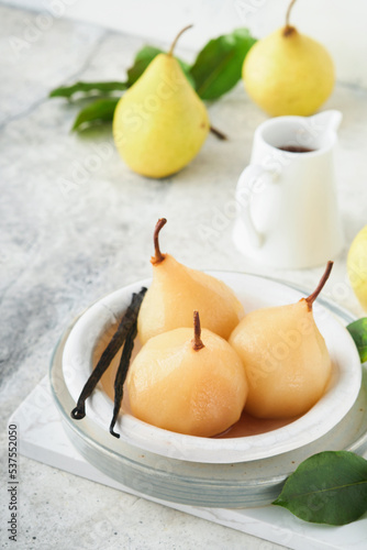 Pears. Poached pears in syrup. Traditional dessert sliced server in a white plate with leaves and at home on a light background. Delicious dessert for holiday.