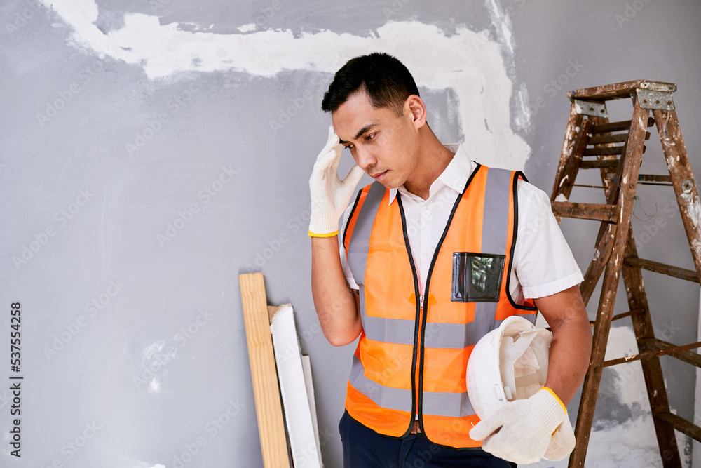 A construction worker scratches head in despair on home renovation project A construction worker scratches head in despair on home renovation project
