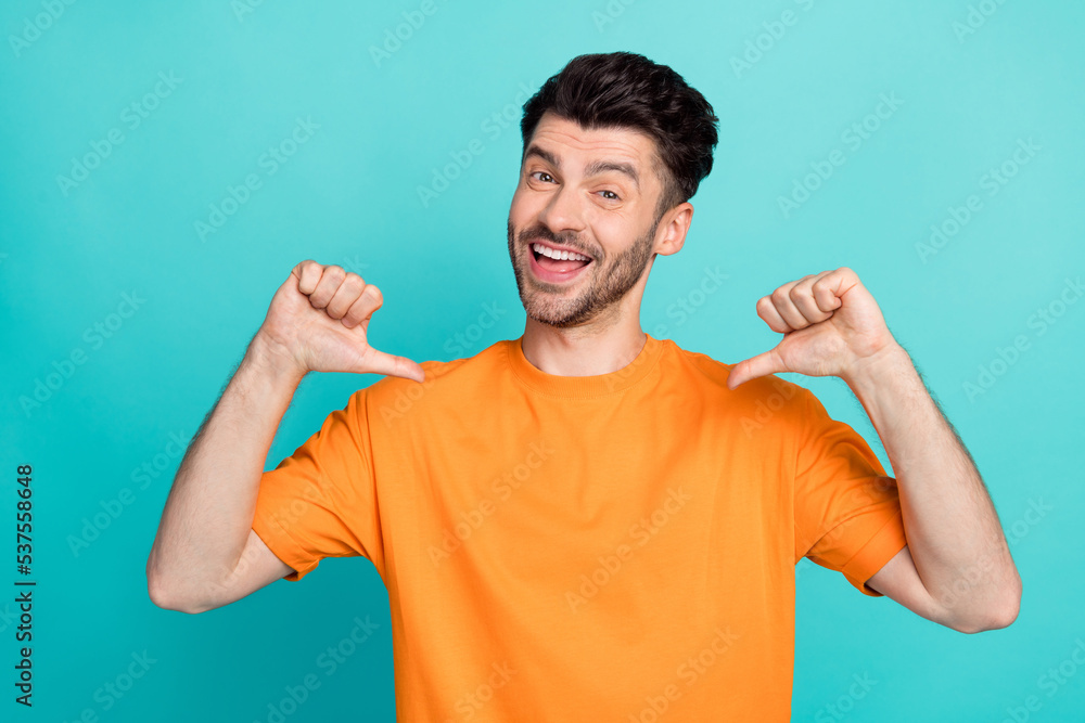 Closeup photo of young funny excited positive toothy smile man wear orange t-shirt showing fingers pointing himself egocentric success isolated on cyan color background Closeup photo of young funny excited positive toothy smile man wear orange t-shirt showing fingers pointing himself egocentric success isolated on cyan color background