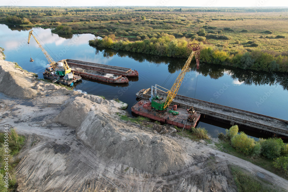 Large floating cranes unload bulk materials on the banks of the river. Large floating cranes unload bulk materials on the banks of the river.
