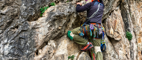 man climbs an overhanging rock with rope, lead climbing. Adventurous Extreme Sport concept. photo