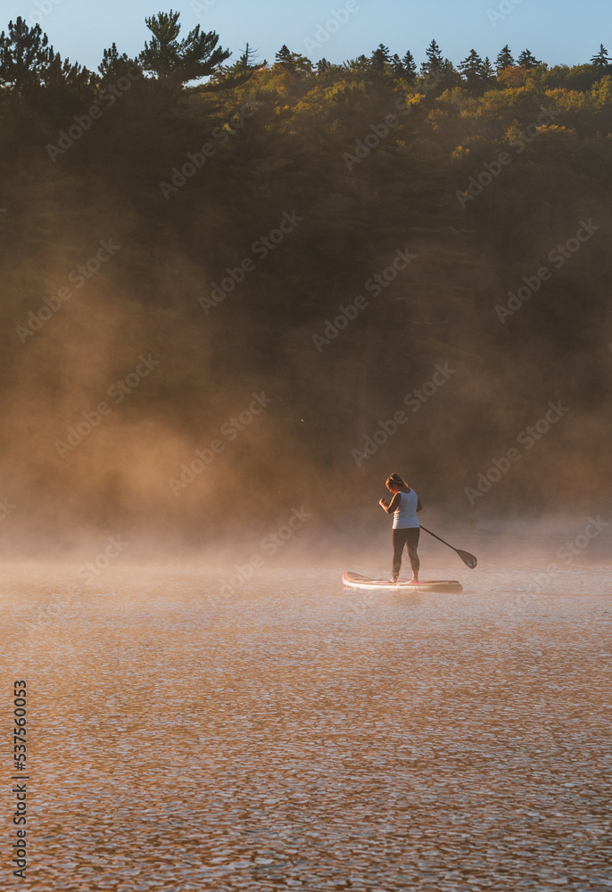 Woman paddling on sup board on Sunrise