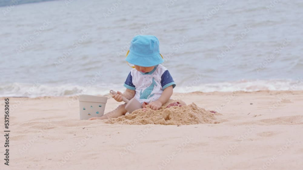 Adorable baby toddler sit on sand play and learn on the beach.First time to touch sand of cute baby excite and happiness. Develop Skill and Experience of baby. Healthy wellness life. Slow motion Adorable baby toddler sit on sand play and learn on the beach.First time to touch sand of cute baby excite and happiness. Develop Skill and Experience of baby. Healthy wellness life. Slow motion