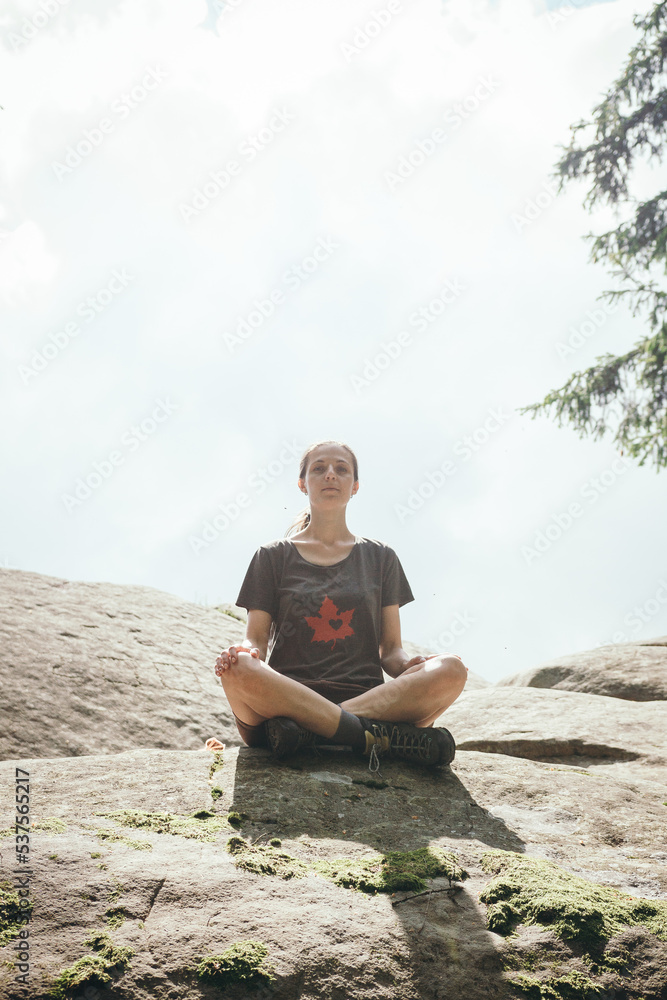 man sitting on the rocks. A girl meditates on a rock. hiking in the mountains. hiker in the forest. The girl travels along the mountain paths. Carpathian Mountains