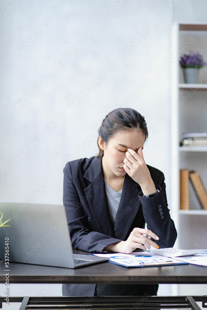 Stressed Asian businesswoman with headache concept from accounting work in front of laptop Women are tired of headaches or chronic fatigue at work. Office Syndrome concept Stressed Asian businesswoman with headache concept from accounting work in front of laptop Women are tired of headaches or chronic fatigue at work. Office Syndrome concept