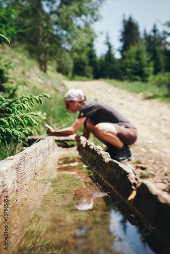 Mountain spring. A girl collects water from a mountain spring. Tourist in the Carpathians