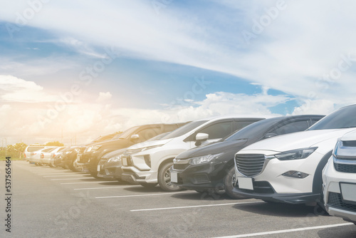 Car parked in large asphalt parking lot with beautiful cloud and blue sky background. Outdoor parking lot travel transportation technology with nature concept