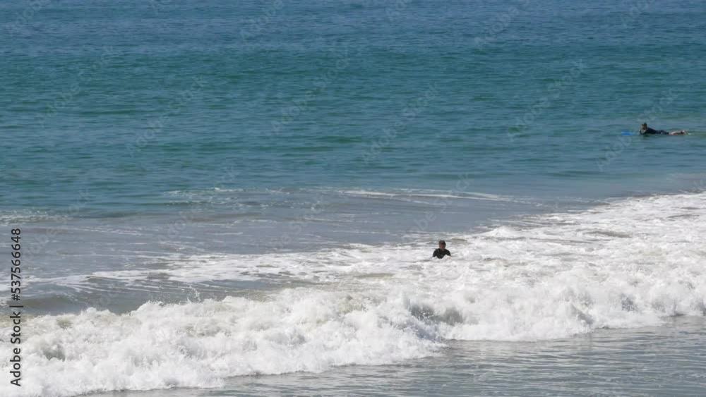 Tracking surfers left to right watching and riding the waves next to the San Clemente Pier in Orange County, California, USA Tracking surfers left to right watching and riding the waves next to the San Clemente Pier in Orange County, California, USA