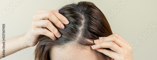 Damaged Hair, face serious asian young woman worry looking at scalp in mirror, hand in break into front hair loss, thin problem symptom at home. Health care shampoo beauty, isolated on background. photo