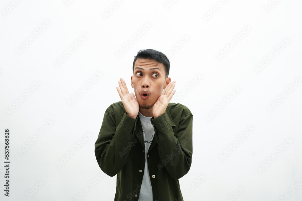 Asian man wearing casual green shirt shocked expression and hands between chin. isolated white background Asian man wearing casual green shirt shocked expression and hands between chin. isolated white background