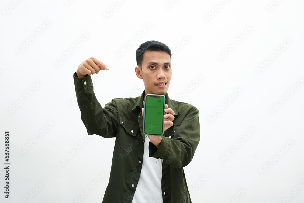 Asian man wearing casual green shirt pointing at smartphone screen. isolated white background. Asian man wearing casual green shirt pointing at smartphone screen. isolated white background.
