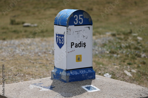 Direction sign distance indicator next to the road. Padis, Romania. Color illustration photo of tourism, traveling.