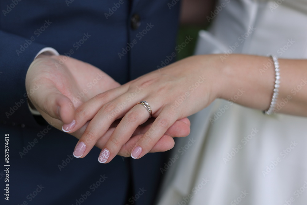 Obraz premium Newlyweds elegant couple are touching and holding each other's hands with engagement ring. Color romantic illustration photo of a happy relationship, wedding or heterosexual lifestyle.