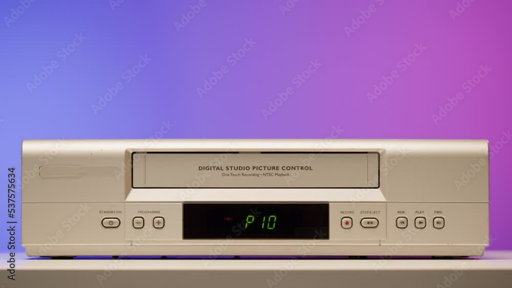 Old video recorder close-up, VHS. Retro player, vintage video cassette broadcasting on purple background, audio tape. Old video recorder close-up, VHS. Retro player, vintage video cassette broadcasting on purple background, audio tape.
