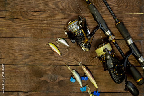 Fishing tackle on a dark wooden background. Wobblers of various modifications, two spinning rods and two reels. Free space for text.
