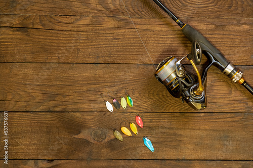 Fishing tackle on a dark wooden background. Light lures in different colors for trout fishing, spinning and reel. Free space for text.