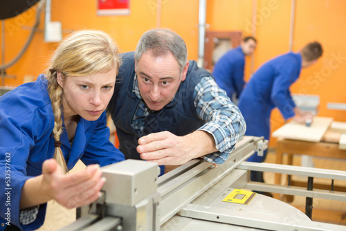 teacher explaining how to use machine in a woodwork class © auremar