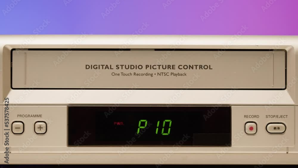 Old video recorder close-up, VHS. Retro player, vintage video cassette broadcasting on purple background, audio tape. Old video recorder close-up, VHS. Retro player, vintage video cassette broadcasting on purple background, audio tape.