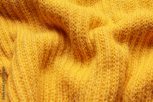 Close-up abstract texture yellow color fabric cloth textile background, knitted wool wavy material, soft folds waves on the fabric. Macro, web theme, template, wallpaper, concept design