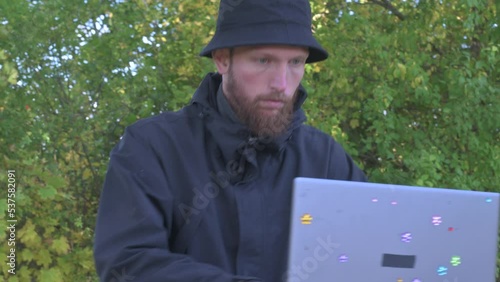 man with a laptop works remotely sitting on a stump in nature