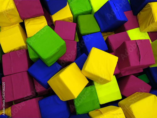 soft colored cubes in the children is playroom. Background. Lots of soft colored cubes. Entertainment, fun, laughter. Building material, constructor. The cubes are multicolored.