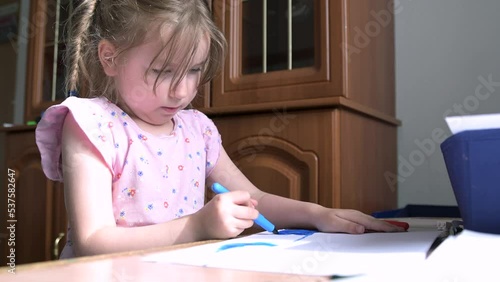 Little girl draws at home on a sheet of paper
