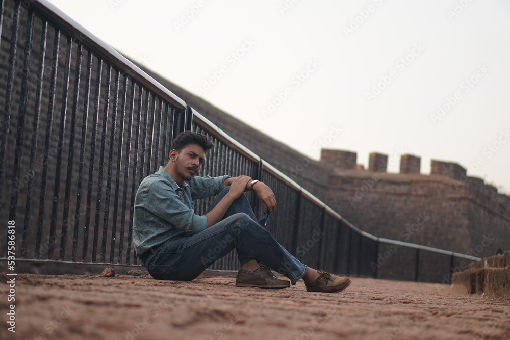 man sitting on old building roadside man sitting on old building roadside