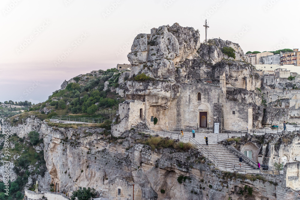 old stone houses and churches on the ravine slopes in the historic center of the old town of Matera. Narrow cobbled streets and cascading buildings with rocks and tightly built-up streets