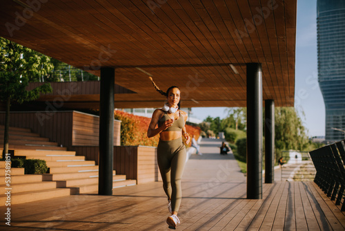 Active young beautiful woman running on the promenade along the riverside