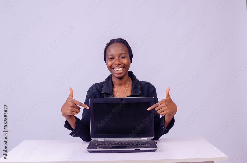 portrait of an excited beautiful young black woman pointing to her laptop screen portrait of an excited beautiful young black woman pointing to her laptop screen