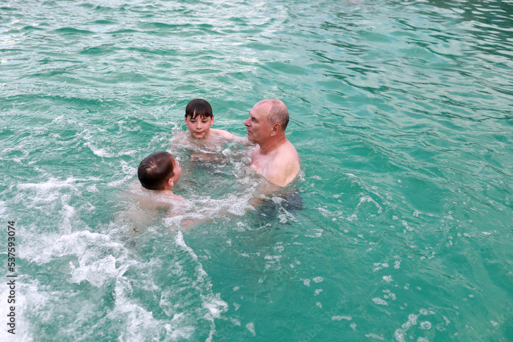 Grandfather and grandsons swimming in warm thermal pool