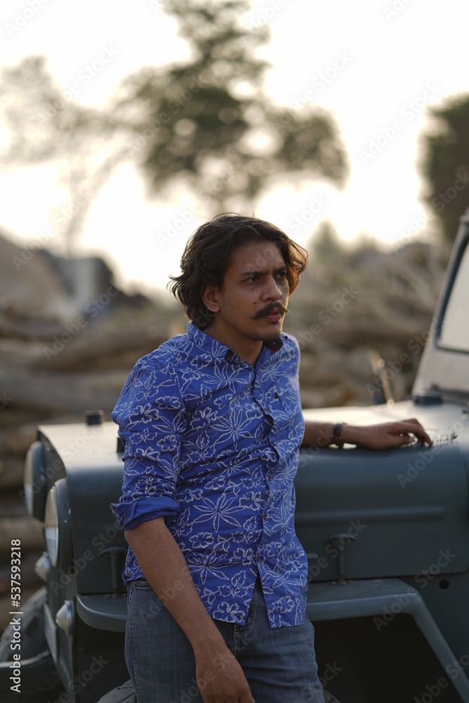 Fototapeta premium man with long hair posing with a jeep