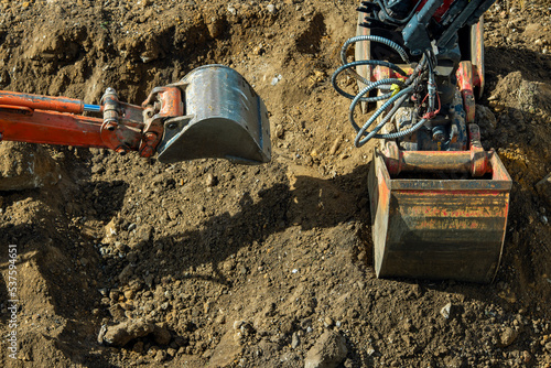 Large and small excavator buckets dig the ground